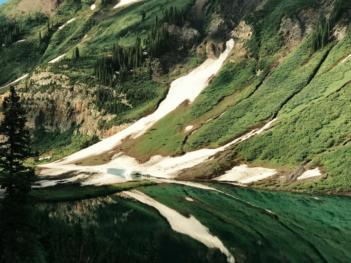 A green mountain valley and alpine lake in Colorado under daytime light